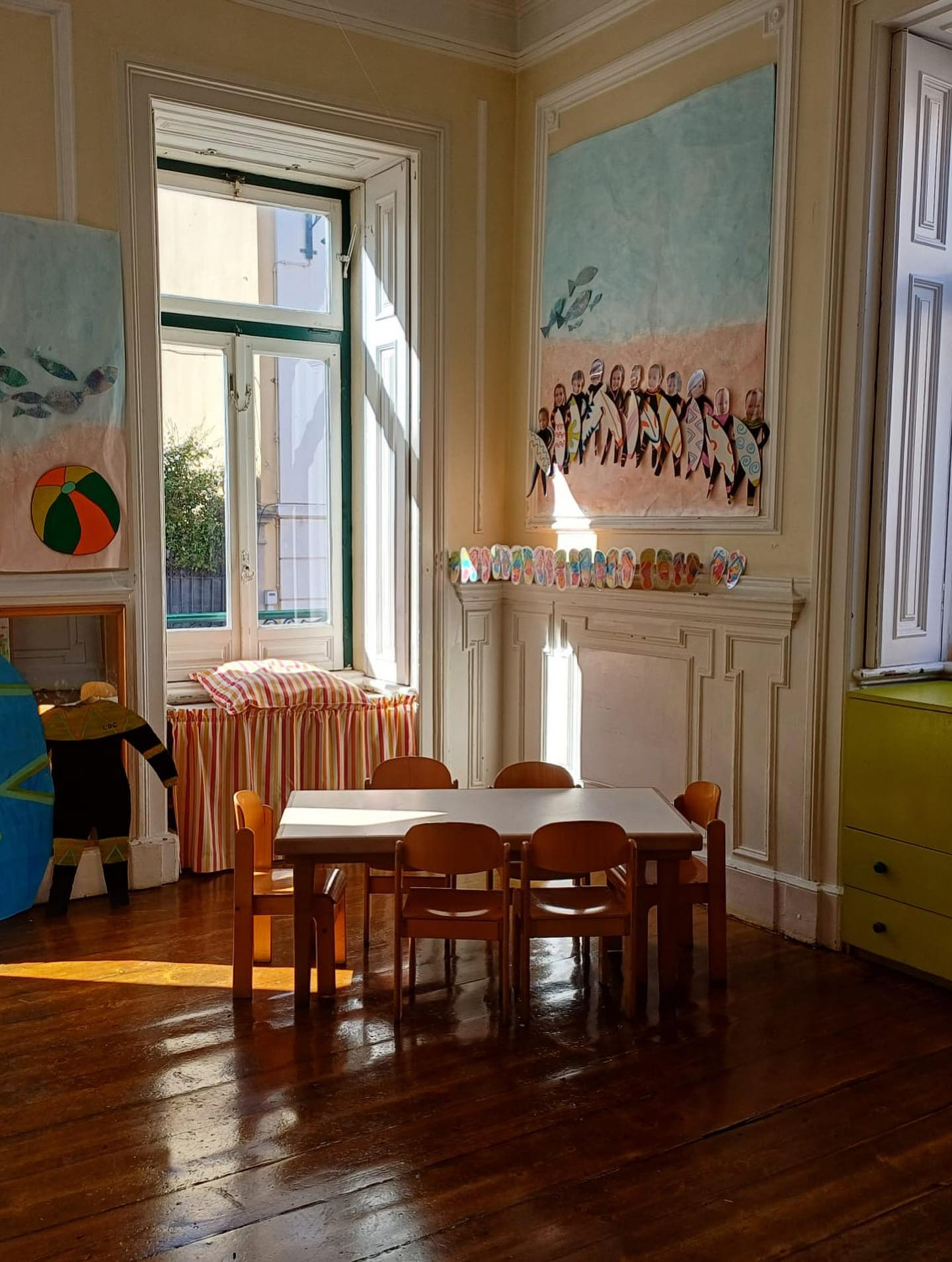 Sala de aula d'O Lar da Criança com luz natural e trabalhos das crianças